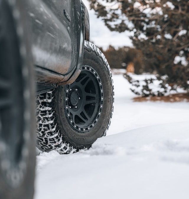 A car with winter tires parked in the snow.