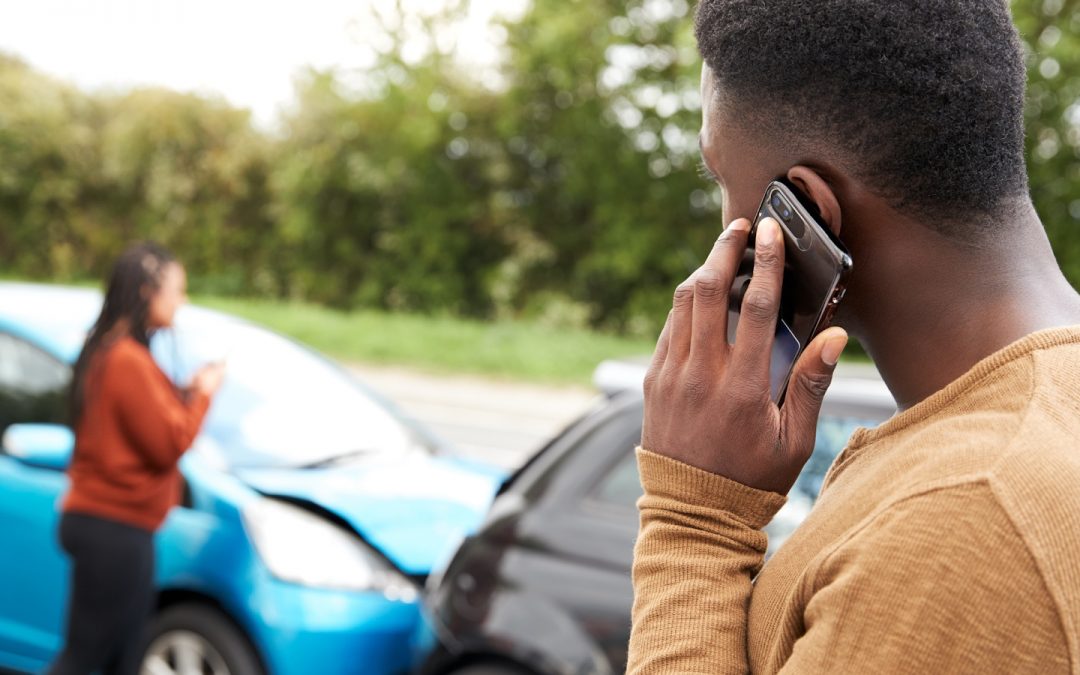Man talks on cell phone while looking at the other driver and the accident scene
