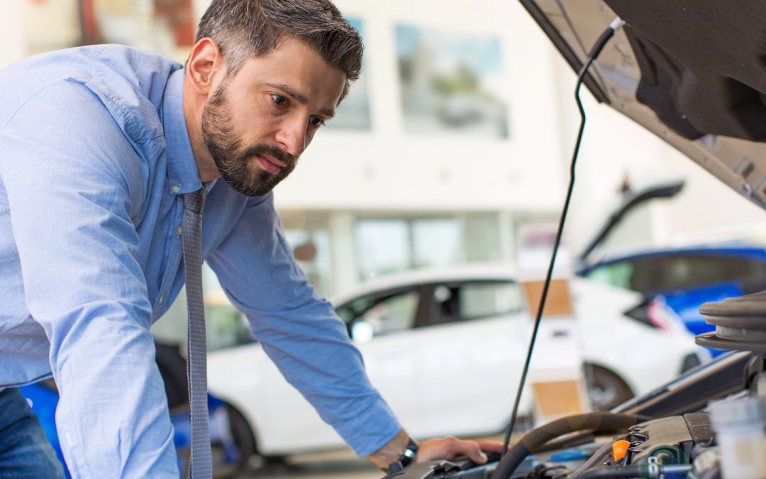 A businessman inspects his engine before a car trip.