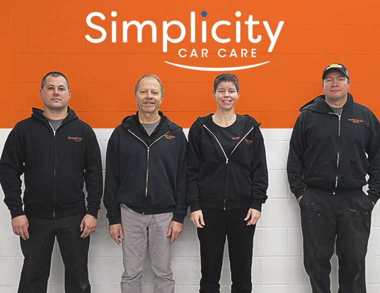 Simplicity Car Care franchisee smiles while standing in his garage.
